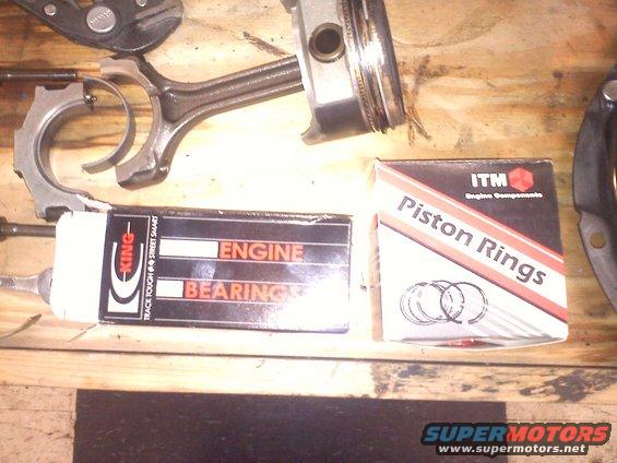 Piston with connecting rod, King engine bearings box, and ITM piston rings box on a wooden surface