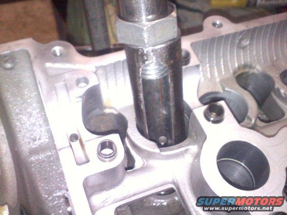 Engine cylinder head with a metal tool inserted into a valve guide