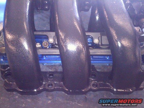 Close-up of a black, cast iron intake manifold with multiple runners
