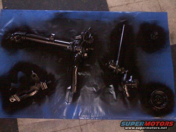 Black painted automotive components on a blue tarp