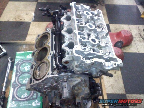 Engine block with pistons and cylinder head disassembled, with gasket set and torque wrench nearby