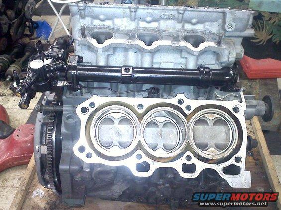Engine block with pistons visible, camshaft and fuel injectors attached