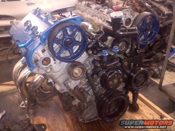 V6 engine with blue painted valve covers and pulleys, chrome exhaust manifold