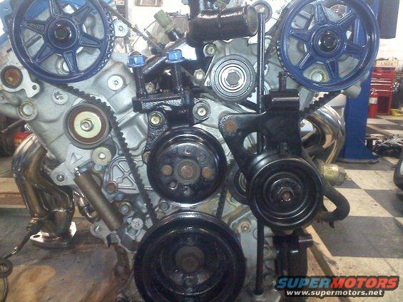 Engine with blue-painted pulleys and black accessories, showing timing belt and exhaust manifold