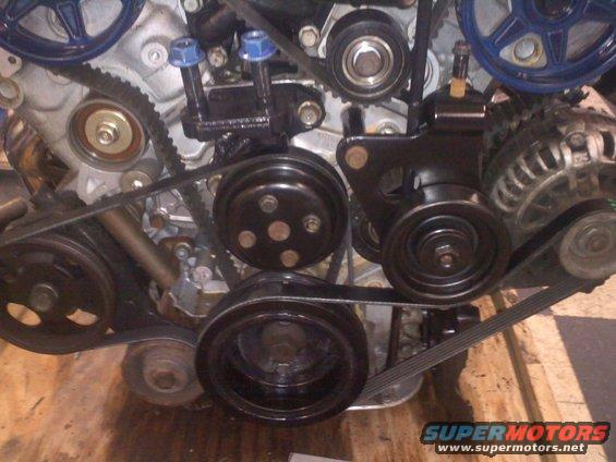 Engine belt system with multiple pulleys and belts, some blue accents visible