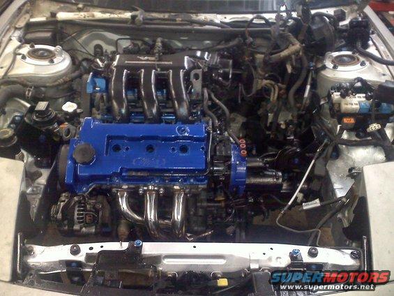 Engine bay with blue painted engine block and chrome exhaust manifold