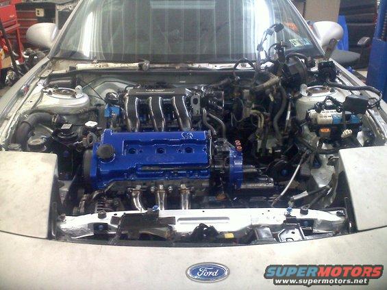 Silver Ford Probe with engine removed, showing the engine bay and a blue engine block