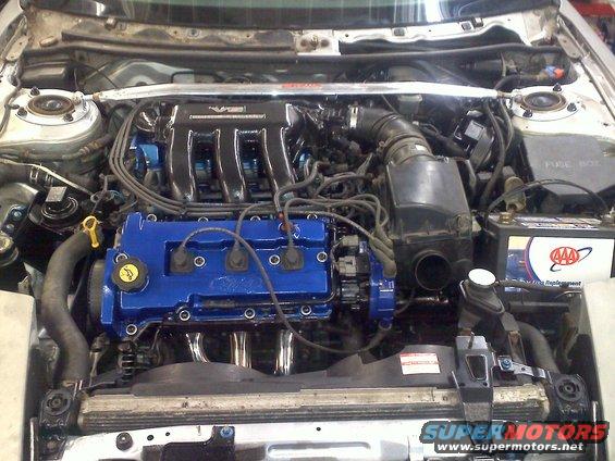 1993 Ford Probe GT engine bay with blue valve covers and aftermarket headers