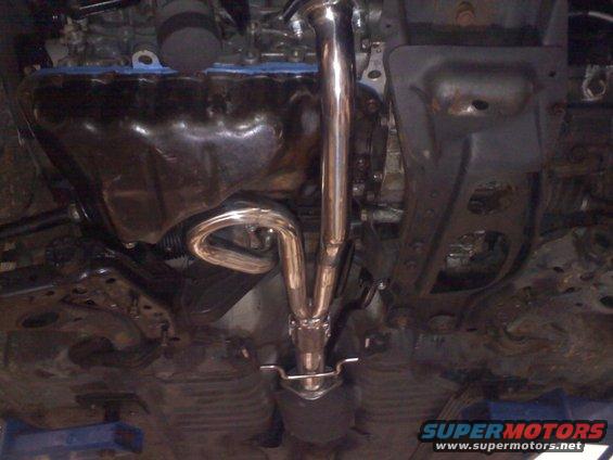 Underside view of a car's exhaust system, showing shiny pipes and the oil pan