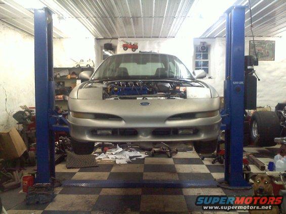 Silver 1993 Ford Probe GT on a lift, hood open, front view, in a garage