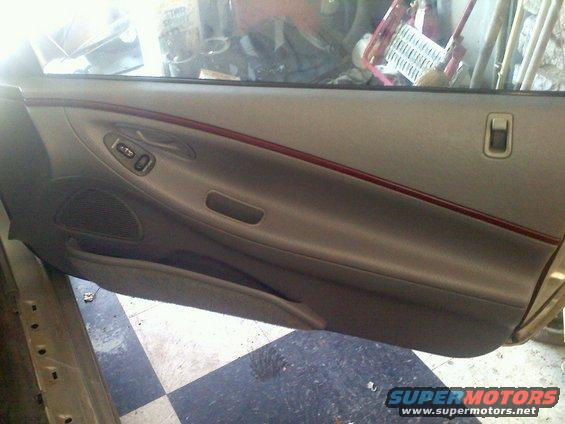 Tan car door interior with red trim and power window controls