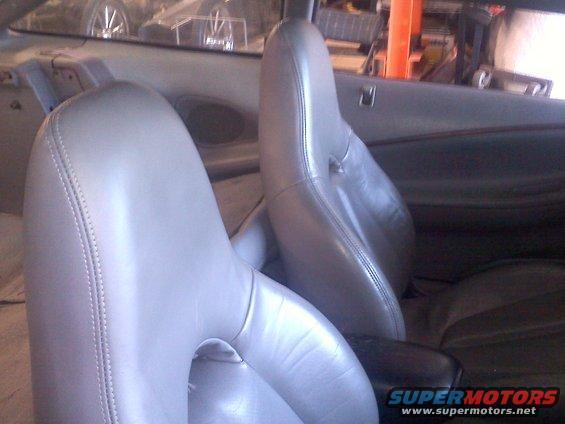 Interior shot of car seats, showing light gray leather front seats and a dark center console