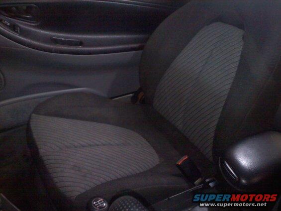 Car interior showing a fabric seat with striped pattern and a black armrest