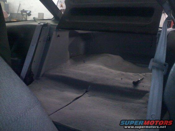 Interior rear cargo area with dusty floor and seatbelt