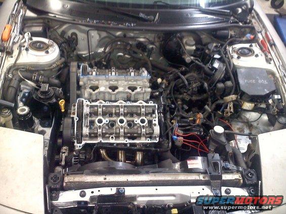 engine bay with valve covers removed, showing camshafts and timing belt
