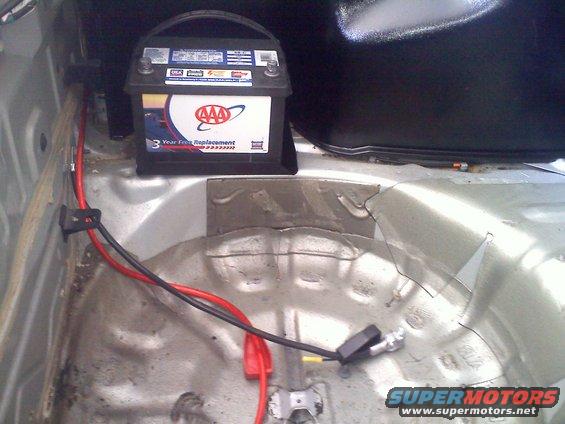 Car trunk showing a AAA battery and red and black wiring connected to the battery terminal