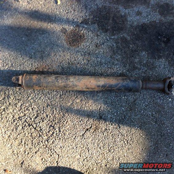 Rusted driveshaft with U-joints on asphalt