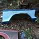 1979 Ford Bronco - A detached vehicle fender part rests on the ground amidst fallen leaves and debris.