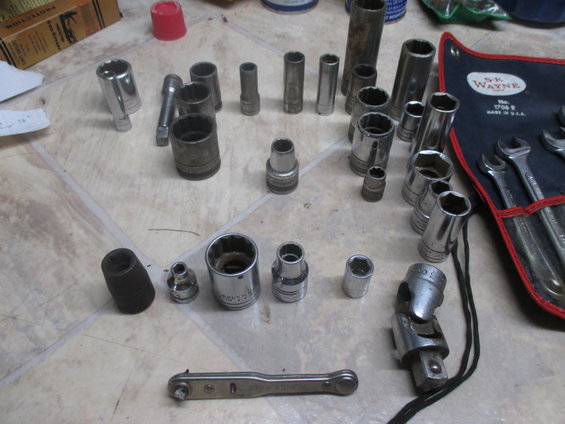 Socket wrenches and a ratchet are laid out on a floor