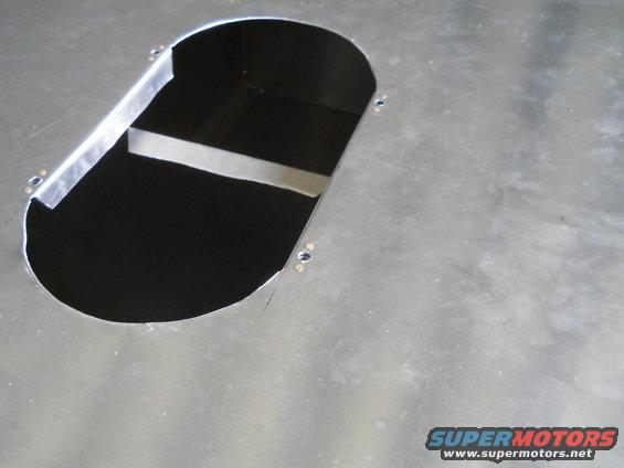 Metal panel with an oval cutout, showing interior bracing and screw holes