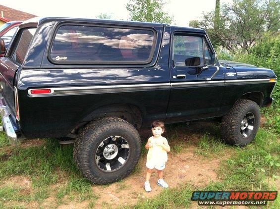 Black Ford Bronco with a child standing next to it