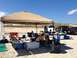 1979 Ford Bronco - People relax under a canopy on a beach with several trucks parked nearby.