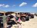 1979 Ford Bronco - A group of people relax on the beach next to a Jeep CJ-7 Renegade and a Ford pickup truck.