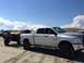 1979 Ford Bronco - A silver pickup truck tows a trailer across a sandy beach under a partly cloudy sky.