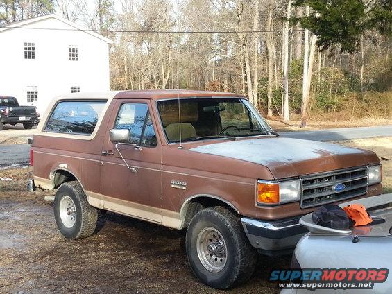 Brown Ford Bronco parked outside a house. Another truck is visible in the background