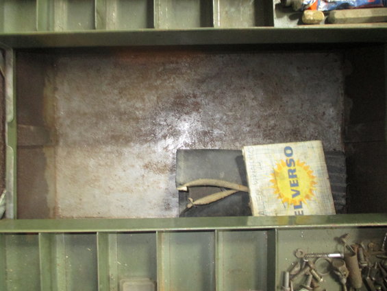 Green metal shelving unit interior with a box labeled 'EL VERSO' and some tools