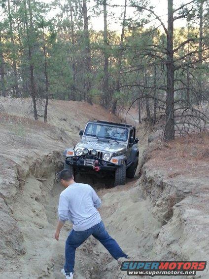 Silver Jeep Wrangler with winch on a dirt trail, driver's side visible