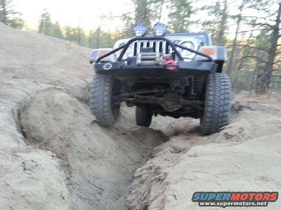 Jeep Wrangler driving through a dirt trench on a hill