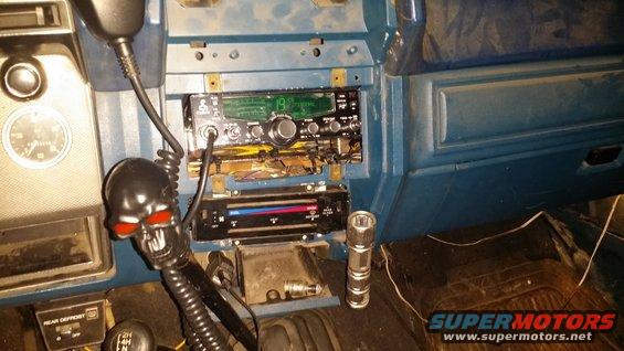 Dashboard of a vehicle showing a CB radio, air conditioning controls, and a skull-shaped gear shift knob