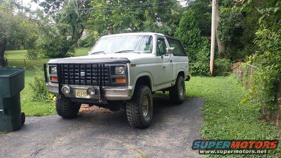 White 1980s Ford Bronco with a black grille guard and off-road tires parked on a driveway