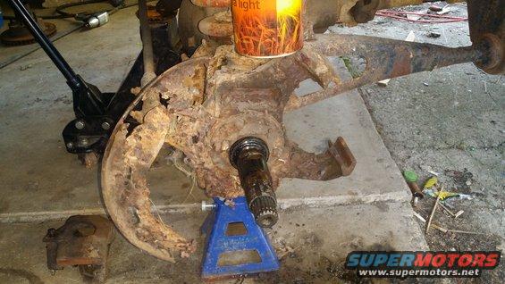 Heavily rusted vehicle suspension component supported by a jack and jack stand