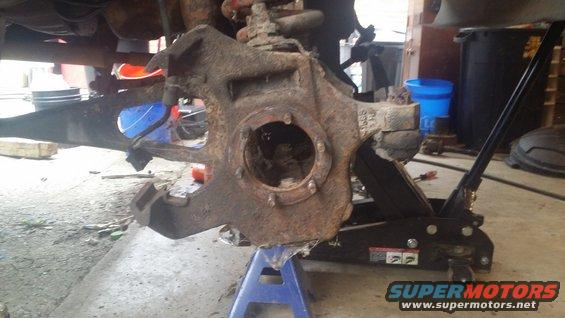 Rusted vehicle suspension knuckle assembly on jack stands and hydraulic jack
