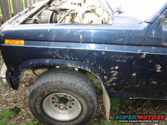 Mud-splattered blue SUV fender and engine bay
