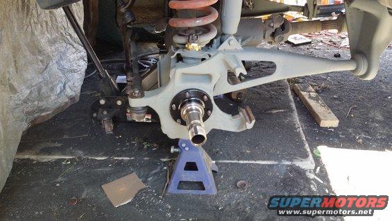 Vehicle suspension assembly on jack stands, showing brake rotor, hub, and coil spring