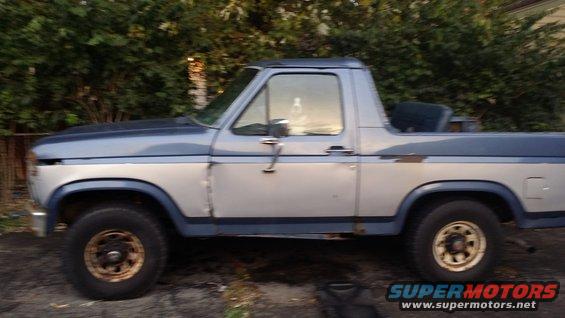 Side view of a two-tone blue and silver Ford Bronco with some rust