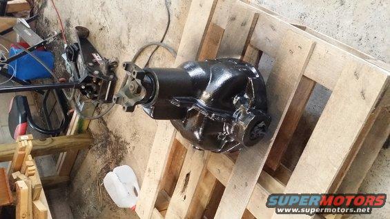 Black differential housing with driveshaft yoke attached, resting on wooden pallets