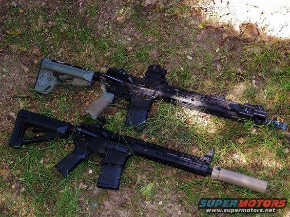 Two assault rifles with suppressors on grass. One has a green stock