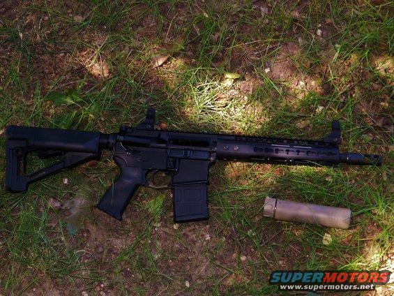 AR-15 rifle and suppressor lying on grass