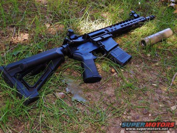 assault rifle with suppressor lying on grass