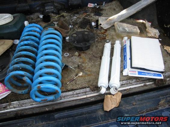Two blue coil springs and two white shock absorbers in a vehicle bed