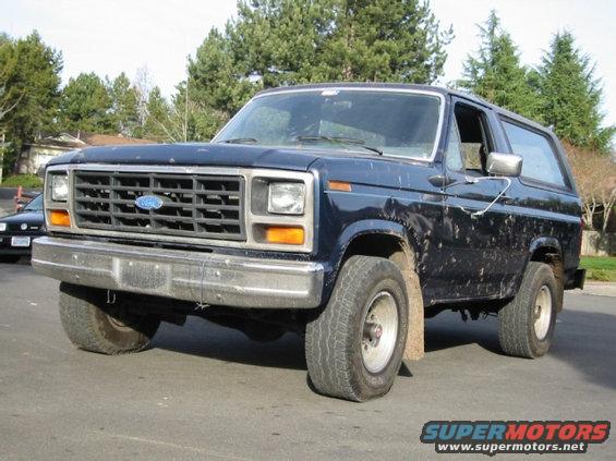 Dark blue 1985 Ford Bronco front three-quarter view with a flat front tire