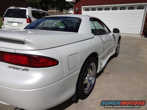White convertible sports car parked in front of a garage with another white SUV behind it