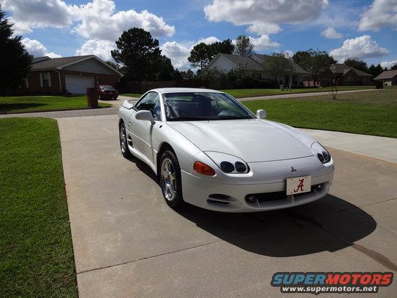 White Mitsubishi 3000GT parked on a driveway, front quarter view. It has a license plate with an 'A' on it
