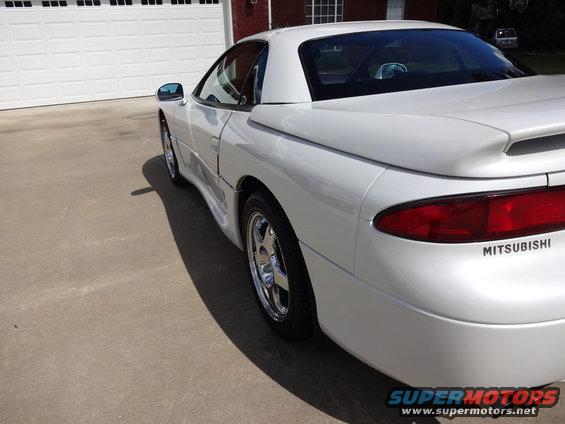 White 1995 Mitsubishi 3000GT parked in front of a garage, rear 3/4 view. MITSUBISHI text visible on rear