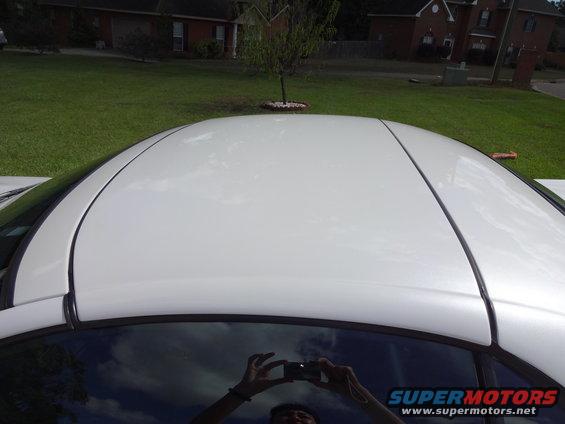 Top view of a white sports car roof with a reflection of someone taking a photo