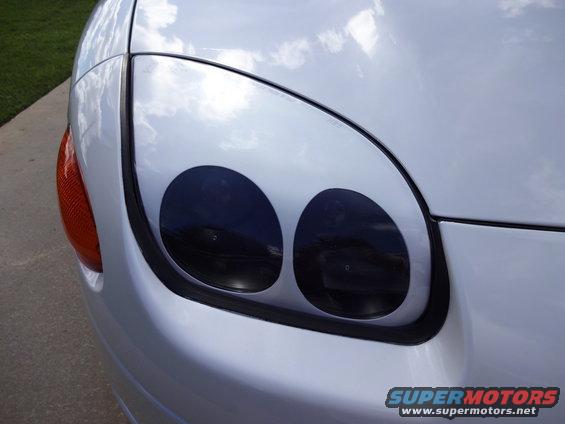 White car headlight with two black circles, orange turn signal visible